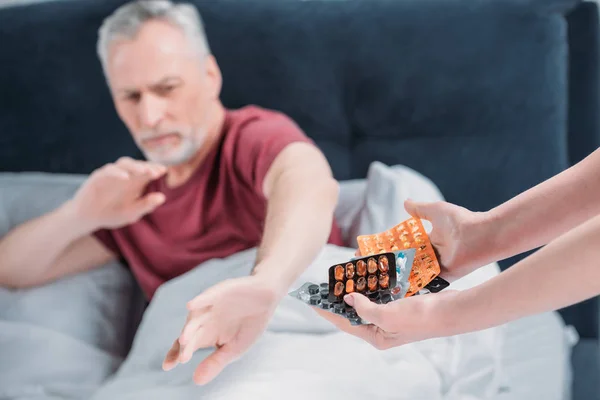 Mujer dando medicamentos al marido - foto de stock