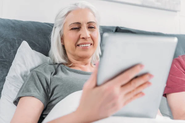 Femme avec comprimé au lit — Photo de stock