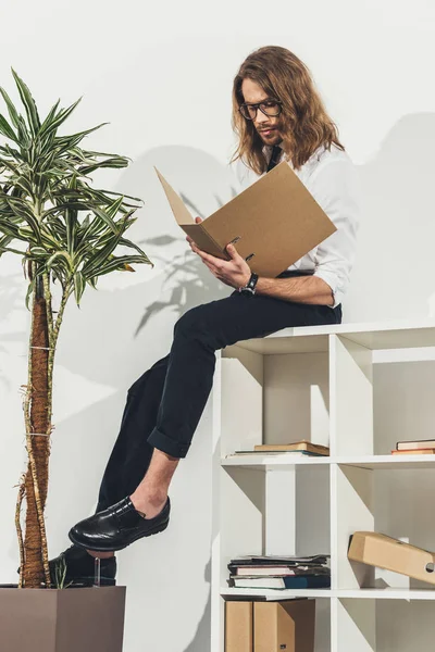 Geschäftsmann mit Ordner im Bücherregal — Stockfoto