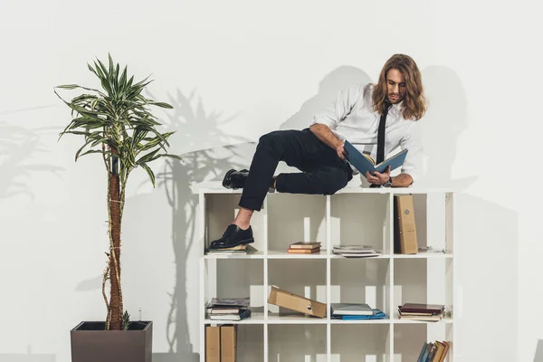 Businessman lying on bookshelf — Stock Photo