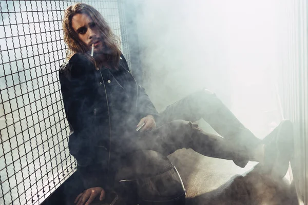 Élégant homme aux cheveux longs avec cigarette — Photo de stock