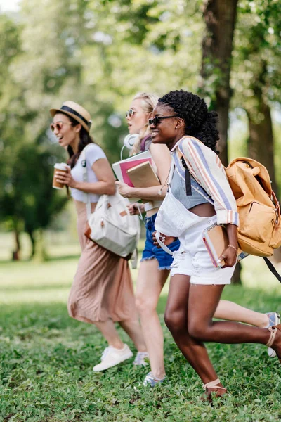 Chicas multiétnicas con libros corriendo - foto de stock