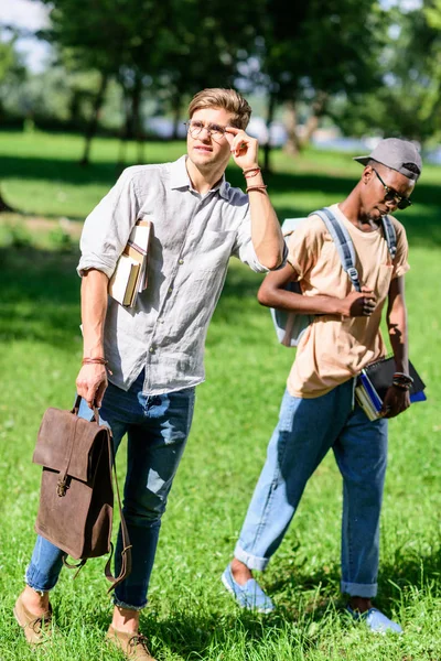 Estudiantes multiétnicos con libros en el parque - foto de stock