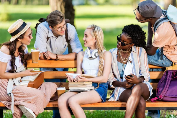Estudiantes multiétnicos en el banco en el parque - foto de stock