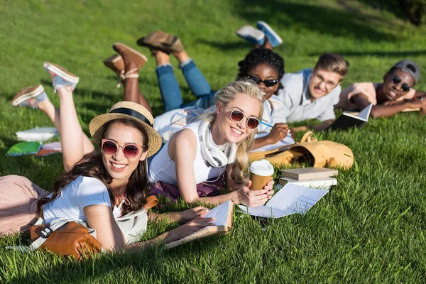 Estudiantes multiétnicos leyendo libros en el parque - foto de stock