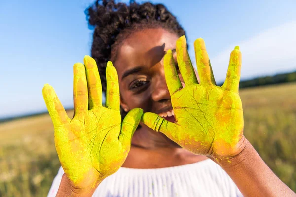 Fille avec de la peinture jaune sur les paumes — Photo de stock