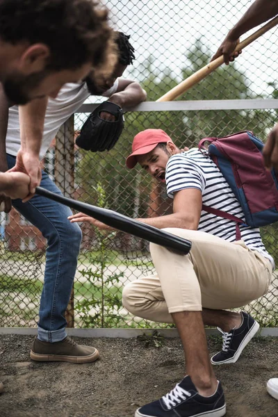 Hombres atacando a otro con bates de béisbol - foto de stock
