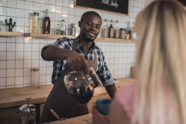 Africano americano barista derramando café — Fotografia de Stock
