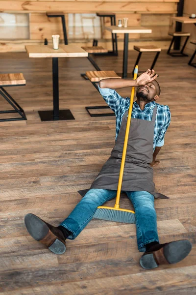 Homme fatigué sur le sol avec balai — Photo de stock