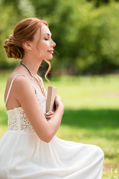 Jeune femme avec livre au parc — Photo de stock