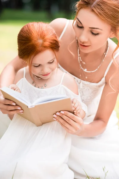 Mère et fille avec livre au parc — Photo de stock