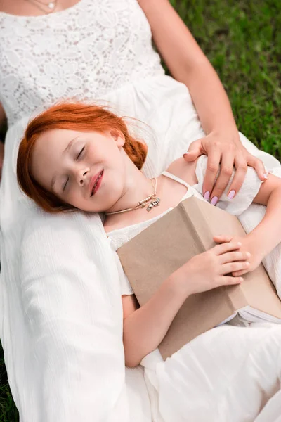 Madre e hija con libro en el parque - foto de stock