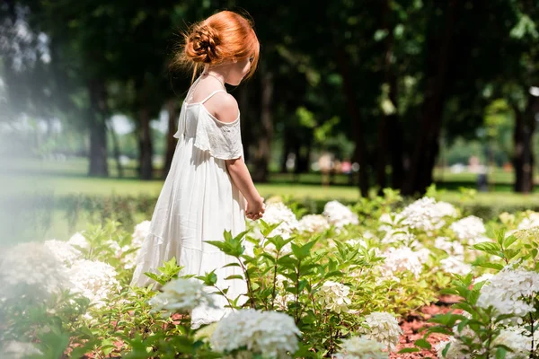 Redhead girl in flower bed — Stock Photo