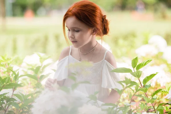 Rousse fille dans lit de fleurs — Photo de stock