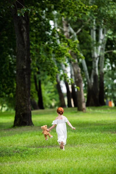 Chica con osito de peluche en el parque - foto de stock