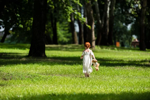 Menina com ursinho de pelúcia no parque — Fotografia de Stock