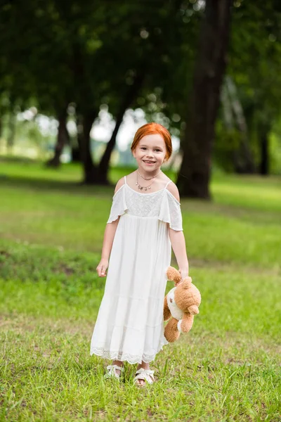 Chica con osito de peluche en el parque - foto de stock