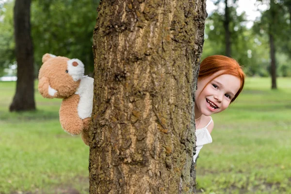 Chica con osito de peluche en el parque - foto de stock