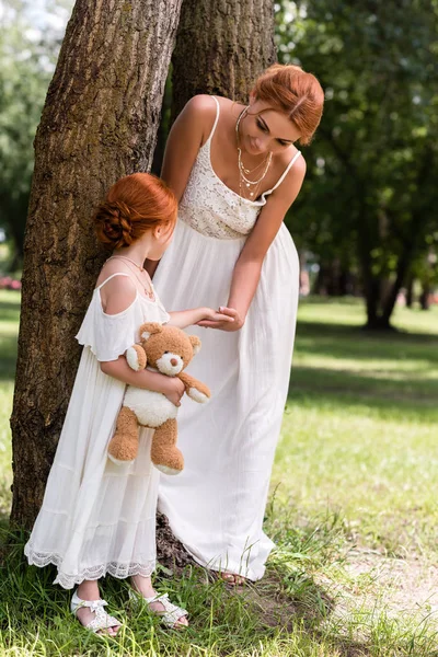 Mother and daughter with teddy bear in park — Stock Photo