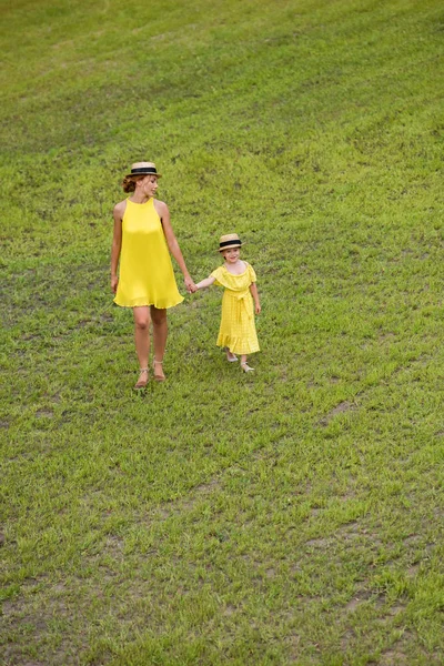 Madre e hija caminando sobre el césped - foto de stock