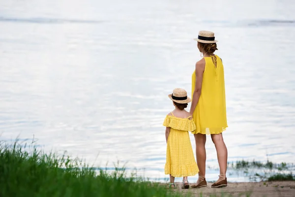 Madre e hija caminando a orillas del río - foto de stock