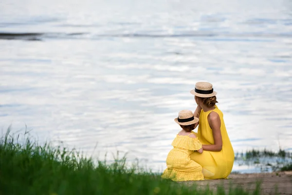 Madre e hija a orillas del río - foto de stock