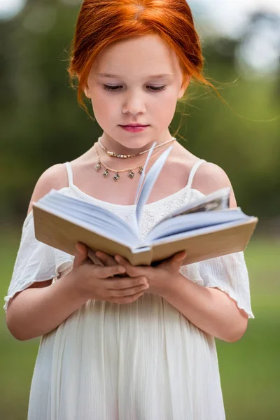 Chica leyendo libro en el parque - foto de stock