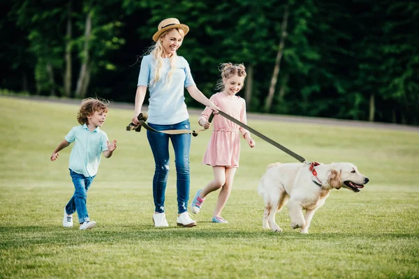 Madre con niños y perro en el parque - foto de stock