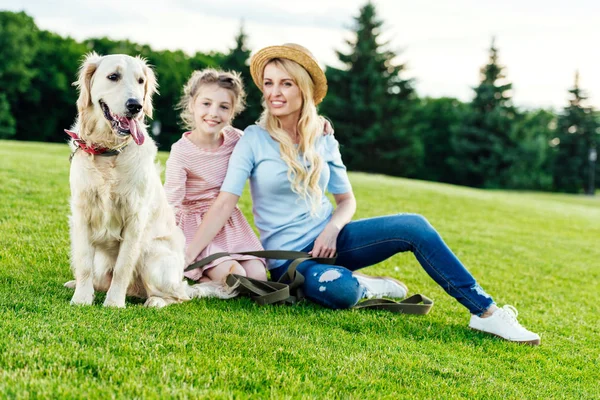 Madre e hija con perro en el parque - foto de stock