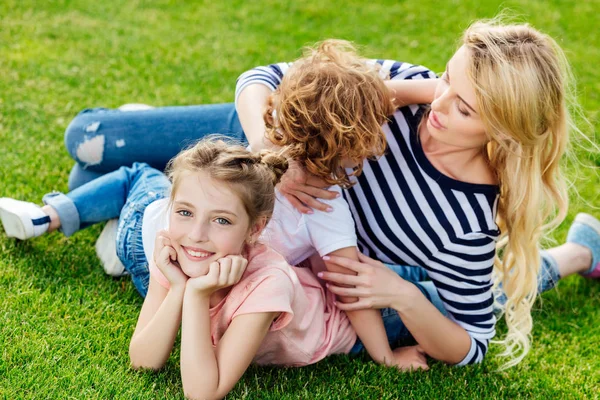 Madre con los niños descansando en la hierba - foto de stock