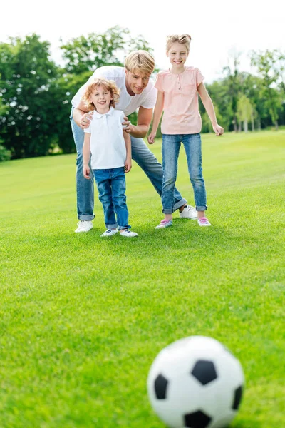 Padre con niños jugando fútbol - foto de stock