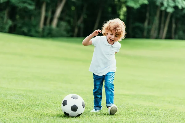 Junge spielt Fußball im Park — Stockfoto