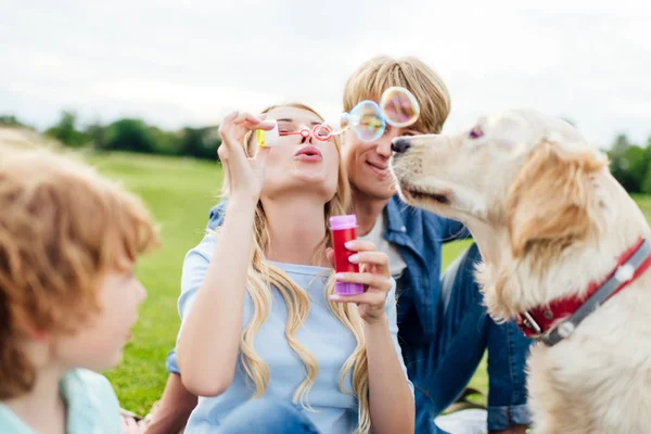 Parents with kid blowing soap bubbles — Stock Photo