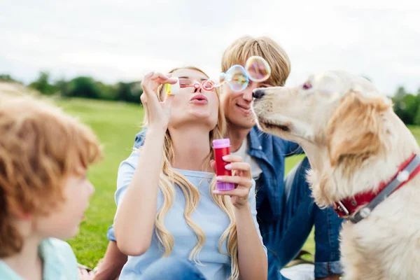 Parents avec enfant soufflant des bulles de savon — Photo de stock