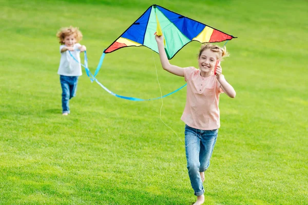 Geschwister spielen mit Drachen im Park — Stockfoto