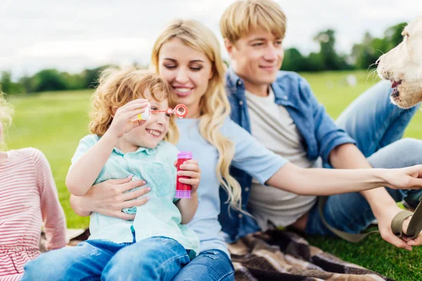 Parents with kid blowing soap bubbles — Stock Photo