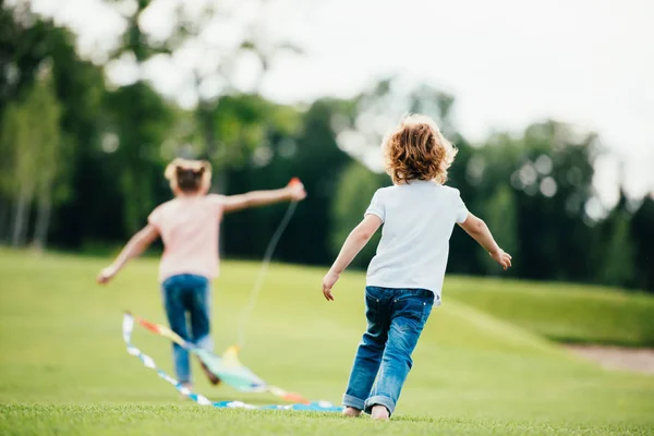 Hermanos jugando con cometa — Stock Photo