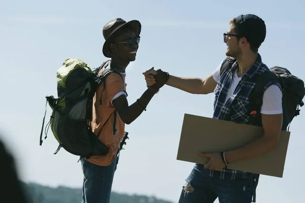 Multicultural hitchhikers shaking hands — Stock Photo