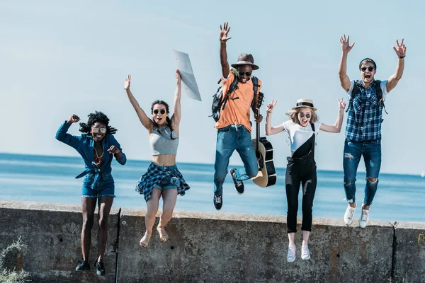 Multicultural friends jumping of parapet — Stock Photo