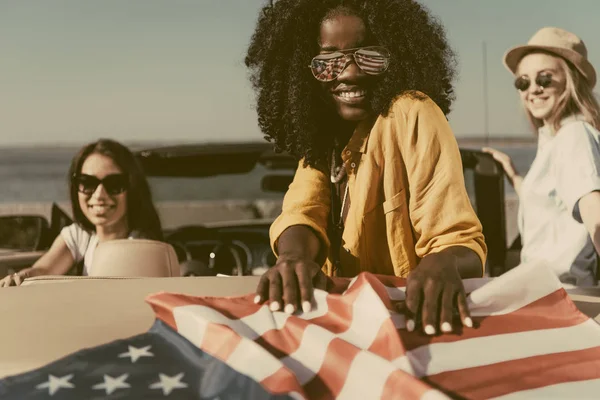 Multiethnic women in car with american flag — Stock Photo