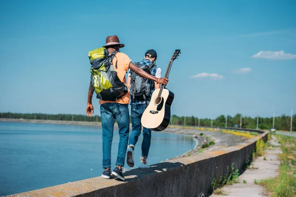 Friends with backpacks walking on parapet — Stock Photo