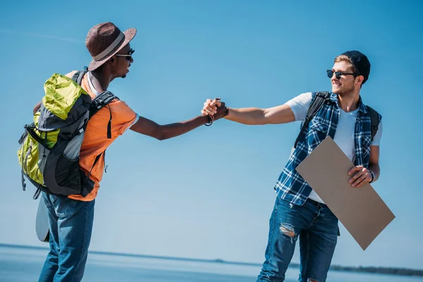 Autoestopistas multiculturales estrechando las manos - foto de stock