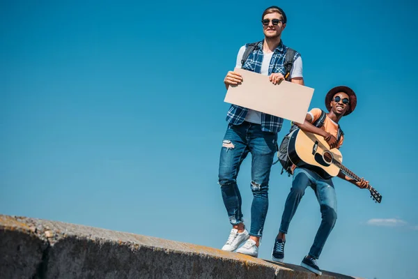 Multicultural men with cardboard hitchhiking — Stock Photo