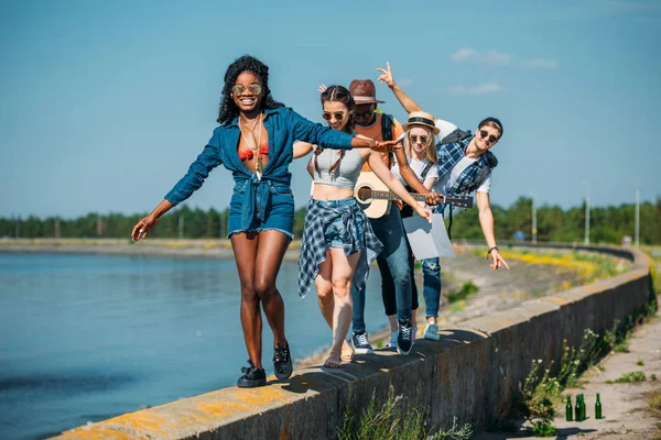 Amici multiculturali che camminano sul parapetto — Foto stock