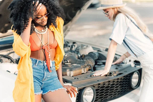 Donne multietniche in piedi vicino rotto auto — Foto stock