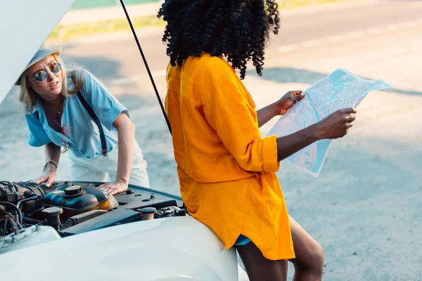 Multiethnic women standing near broken car — Stock Photo