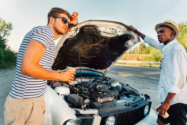 Multiethnic friends with coffee near broken car — Stock Photo