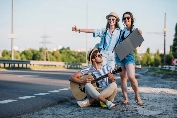 Amigos multiculturales haciendo autostop juntos - foto de stock