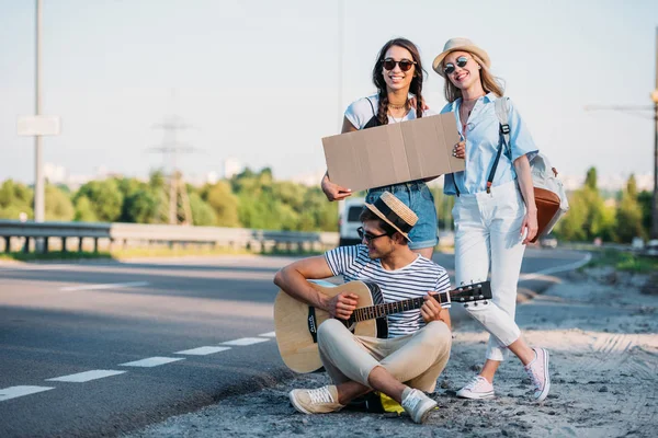 Multicultural friends hitchhiking together — Stock Photo