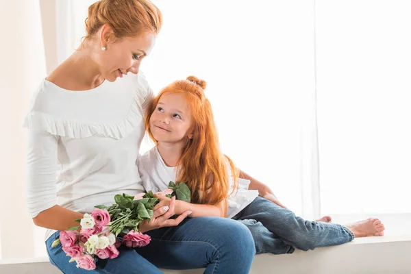 Mère avec des fleurs étreignant petite fille — Photo de stock